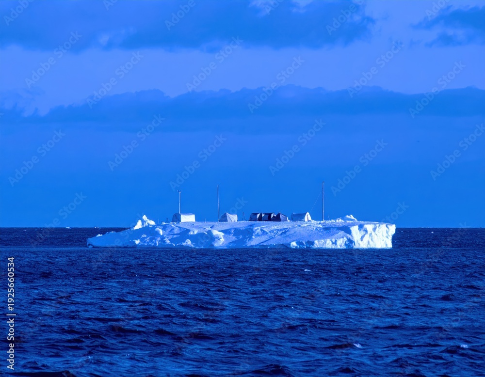 Obraz premium Large iceberg with structures on floating in deep blue ocean under cloudy sky water