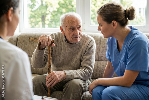 Two nurses talking with elderly man holding walking cane in nursing home senior care meeting