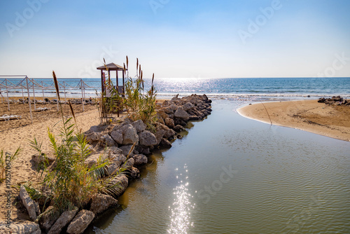 Foto Scenic estuary where a small river meets the Mediterranean sea on a sunny beach