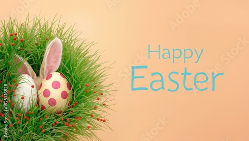 Easter eggs in grass with bunny ears and red flowers on peach background