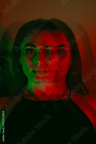 Dreamy portrait of a brunette with bright red flowers in a red green glow with a triple lens and long exposure