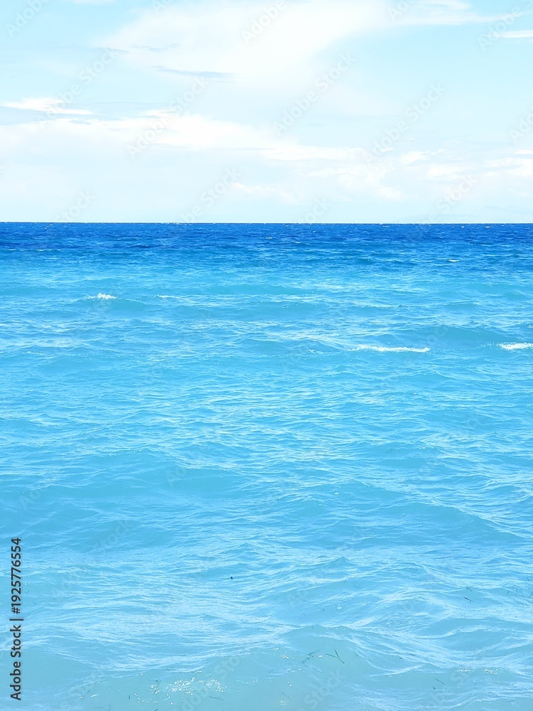 Fototapeta premium vertical view of a calm light blue sea in Greece with white clouds