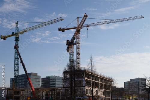 Dynamic urban development scene in Amersfoort featuring several large construction cranes operating over a new concrete structure. 