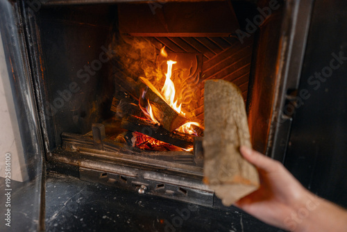 Φωτογραφία Hand placing a log into a lit fireplace, fueling a warm fire for a cozy home int