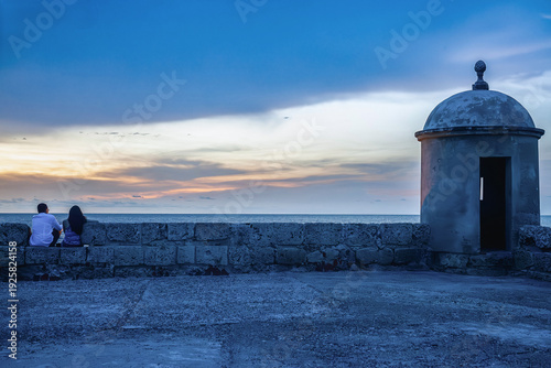 Unrecognizable couple watching sunset from city wall in cartagena