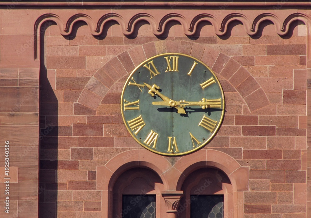 Fototapeta premium Close-up of the historic clock with Roman numerals on Johanneskirche church facade in Freiburg im Breisgau, Germany. Red brick Gothic Revival architecture detail, 25 March 2011
