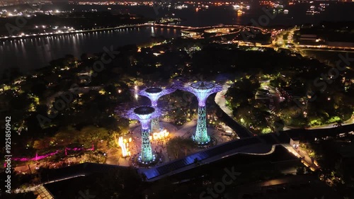 Singapore by Night – 4K aerial drone footage of gardens by the bay, garden Rhapsody, dome and river illuminated in financial district (CBD).