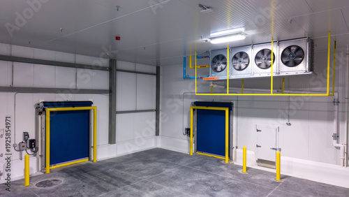 industrial cold storage room with large, ceiling-mounted  with evaporator fan units, used to remove heat from the room to maintain low temperatures, and High Speed Roll Up Doors  