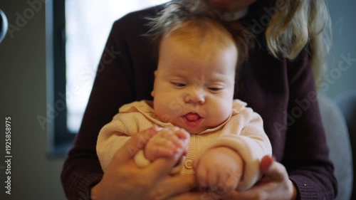 Wallpaper Mural Close up of a baby sitting on an adult's lap indoors while gently holding hands Torontodigital.ca