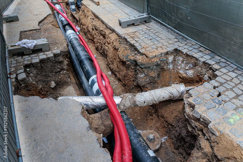 Fotografie City Street Construction With Utility Pipes In Open Trench Along Urban Sidewalk