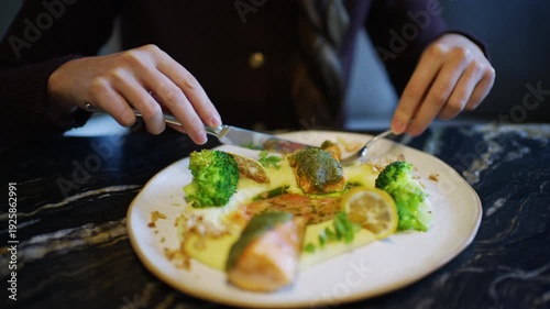 Wallpaper Mural Close up of hands using knife and fork to cut a salmon fillet served with broccoli and sauce Torontodigital.ca