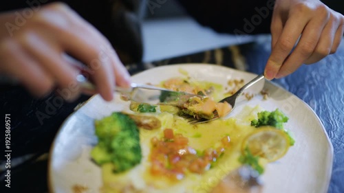 Wallpaper Mural Close up of hands using knife and fork to cut a salmon fillet served with broccoli and sauce Torontodigital.ca