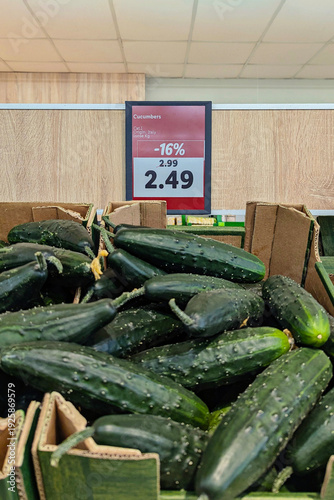 Wallpaper Mural Closeup pile of fresh cucumbers in cardboard crates with price tag and discount percentage in grocery store, consumer inflation mood Torontodigital.ca