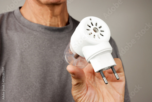 Man Holding up and demonstrating An Electric Plug in Mosquito Repellent for home use