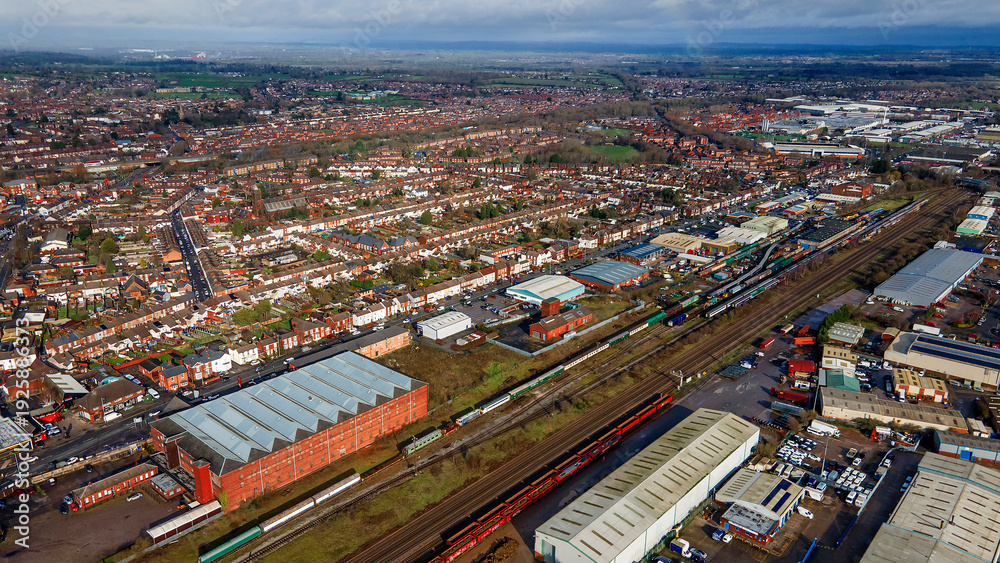 Obraz premium Railway tracks and train wagons crossing through industrial town