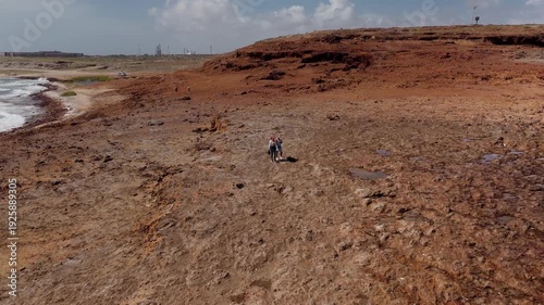 Toma aérea cinematográfica con drone de una pareja disfrutando de la vista del mar y las olas rompiendo en lo alto de las rocas en Aruba