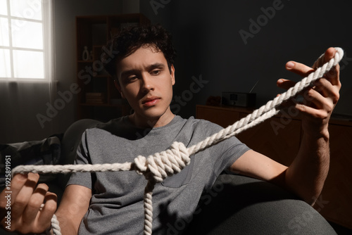 Sad young man with rope sit...