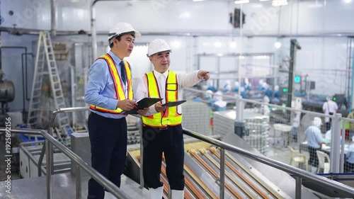 Asian man factory engineers and manager quality control inspection in canned food manufacturing plant review production line with safety equipment and industrial processing inside modern food factory.