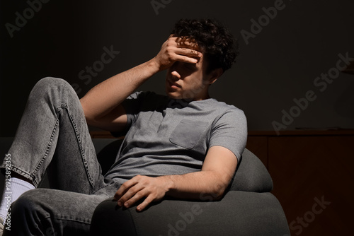 Sad young man sitting on so...