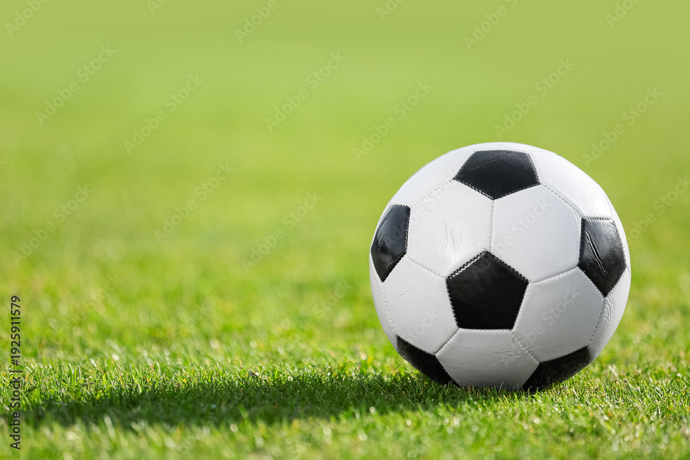 Fototapeta premium Soccer ball on green grass, closeup