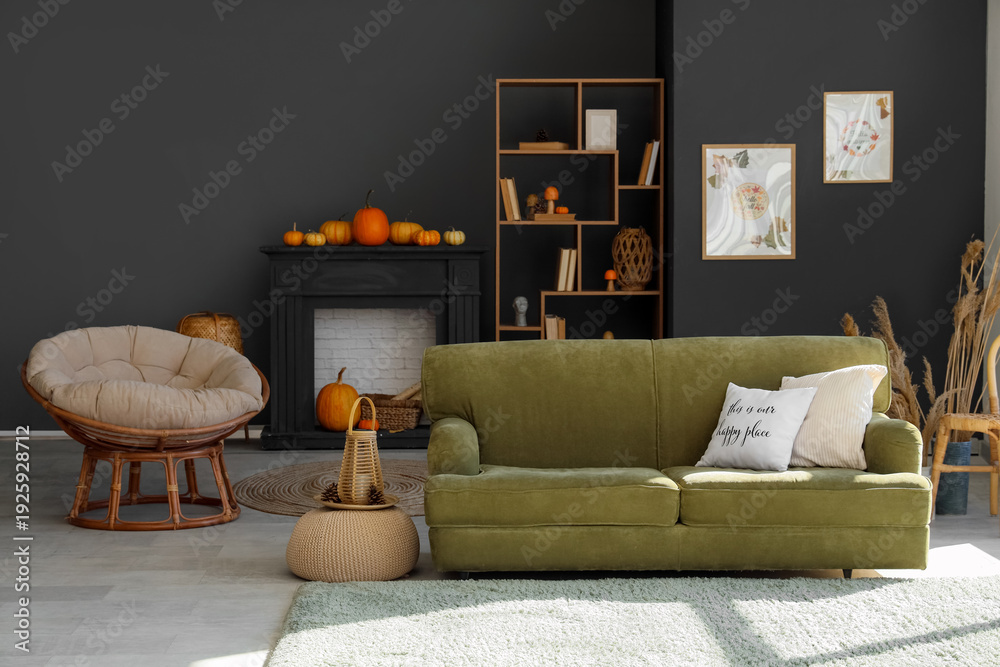 Fototapeta premium Interior of modern living room with green sofa, black fireplace and shelving unit. Autumn concept
