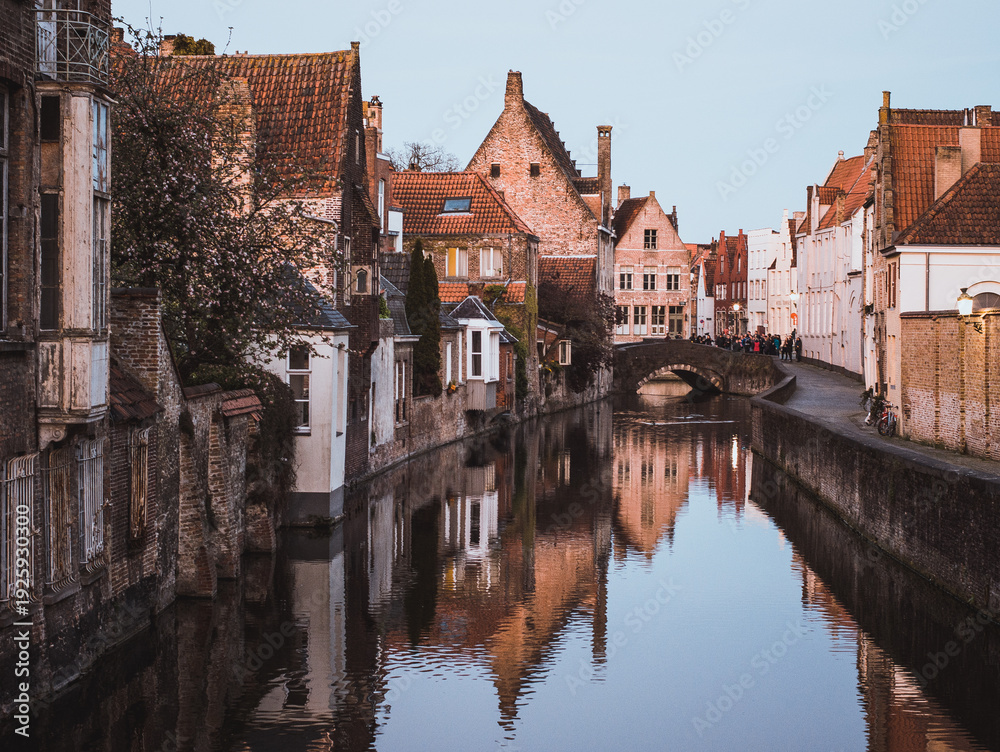 Obraz premium Scenic view of the famous canal in Bruges (Brugge), Belgium, with medieval brick houses reflecting in the water and a stone bridge.