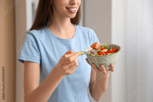 Young woman eating salad in...