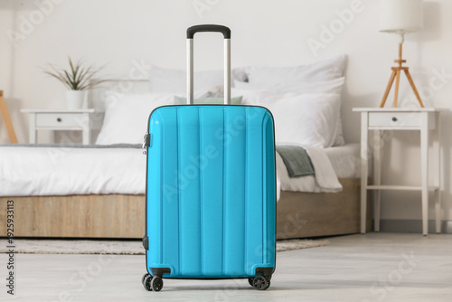 Suitcase near bed in light ...