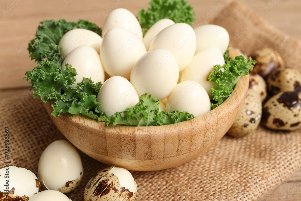 Obraz premium Bowl with fresh boiled quail eggs and lettuce on wooden background