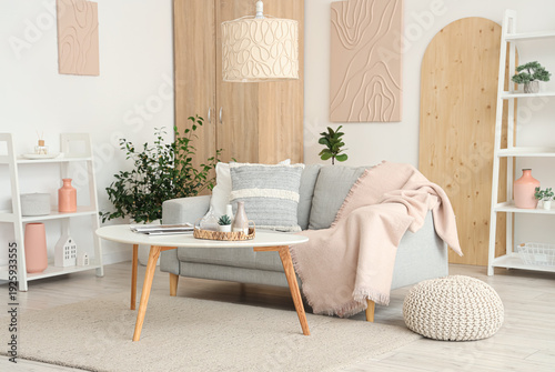 Light interior of stylish living room with sofa, houseplants, shelving unit and coffee table