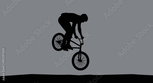 BMX rider silhouette performing a jump trick against a grey background