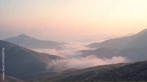 Serene pastel colored mountain landscape stretches into the distance with soft valley fog illuminated by the early morning golden hour sunlight