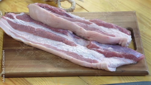 Close up fresh raw pork belly slices on wooden cutting board, uncooked meat texture and fat layers for cooking preparation, ingredient for frying, roasting, or homemade meals
