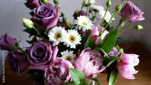 Elegant bouquet of purple roses, pink peonies, and white daisies in bloom.