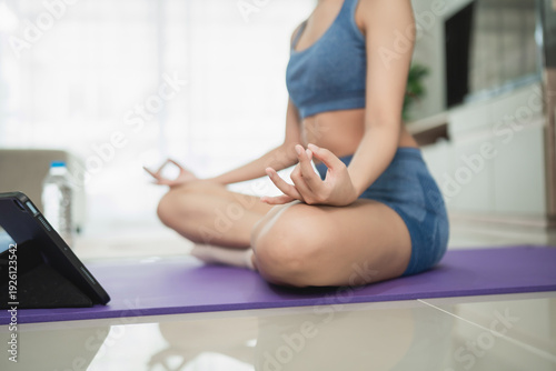 Bilde på lerret Young woman practicing mindfulness and meditation on yoga mat at home using tabl