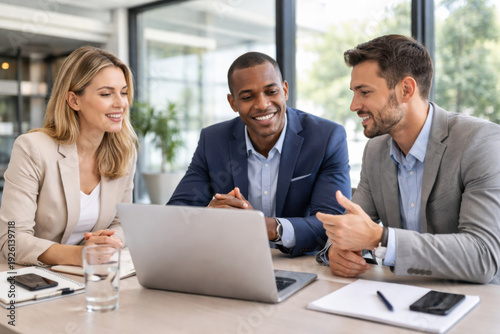 Happy business team in professional meeting and discussion. Three colleagues working on laptop in modern office, showing positive collaboration and teamwork