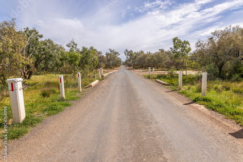 Obraz na plátne The main road floodway across the Bulloo River disappears amongst the riverine trees, and is submerged quite often and floods can cut off the town of Thargomindah close by in Queensland, Australia