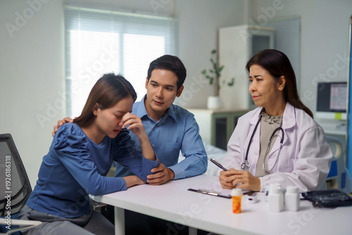 Foto Doctor talking to an upset couple, the woman crying while her partner offers sup