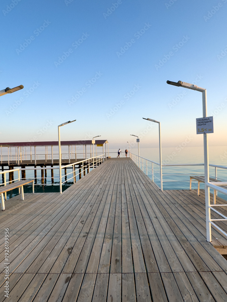 Fototapeta premium Pier at Issyk Kul Lake in Kyrgyzstan. Calm water surface, minimal composition and warm sunset light.