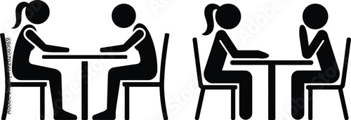 Four individuals engaged in separate conversations at two distinct tables.