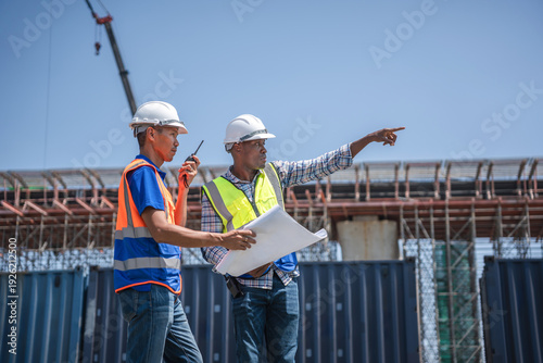 Foto Diverse engineers discussing blueprints and pointing at construction site projec