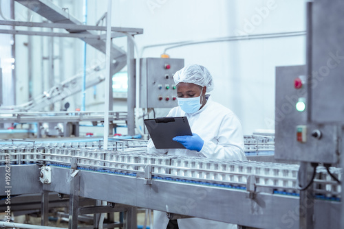 Cuadro en lienzo Production worker reviews packaging consistency of metal cans in automated food factory, recording results to support traceability system and operational transparency