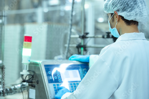 Tablou pe pânză Factory machine operator checks production data on touch screen panel in food manufacturing plant, representing automation system management and regulatory compliance process