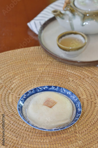 Taro-filled steamed buns with hot tea cup at back