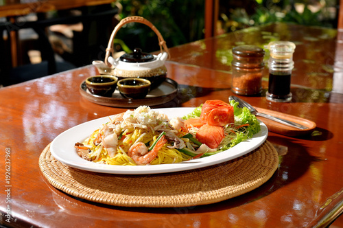 Chinese-styled fried noodle on table with Chinese tea pot set at back