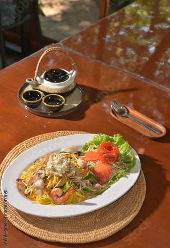 Chinese-styled fried noodle on table with Chinese tea pot set at back