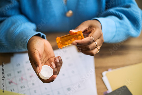 Cuadro en lienzo Black woman opening prescription pill bottle, holding medication in hand, sittin