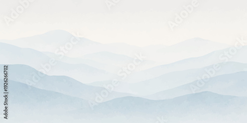 A misty mountain landscape at sunrise reveals a vast valley of hills and forests under a blue morning sky where clouds and fog meet the snowy horizon of the winter range