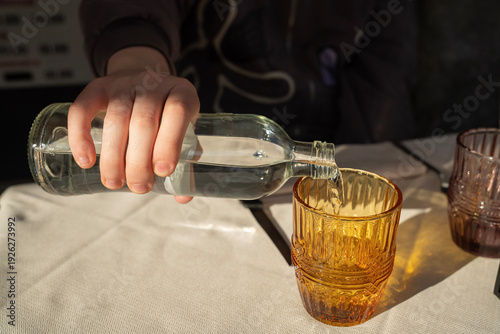 nalewanie wody do szklanki przy stoliku w restauracji w słoneczny upalny dzień