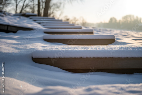 Snow covered wooden steps leading towards a blurred winter landscape